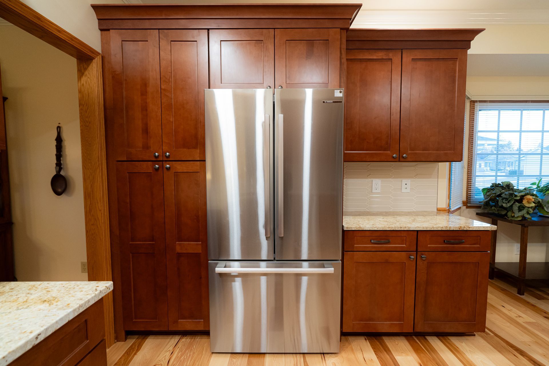 Bright kitchen with stainless steel refrigerator, wood cabinets, and granite countertops