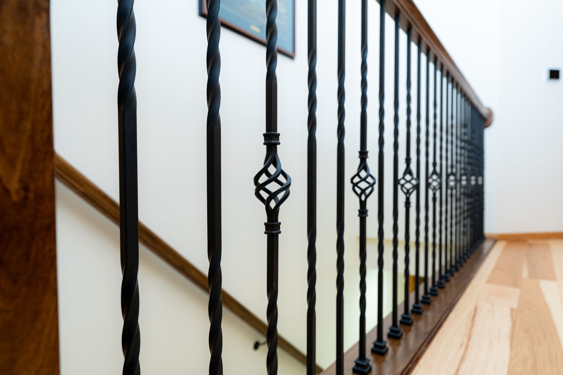 Black wrought-iron stair railing along a light wood staircase in a bright hallway