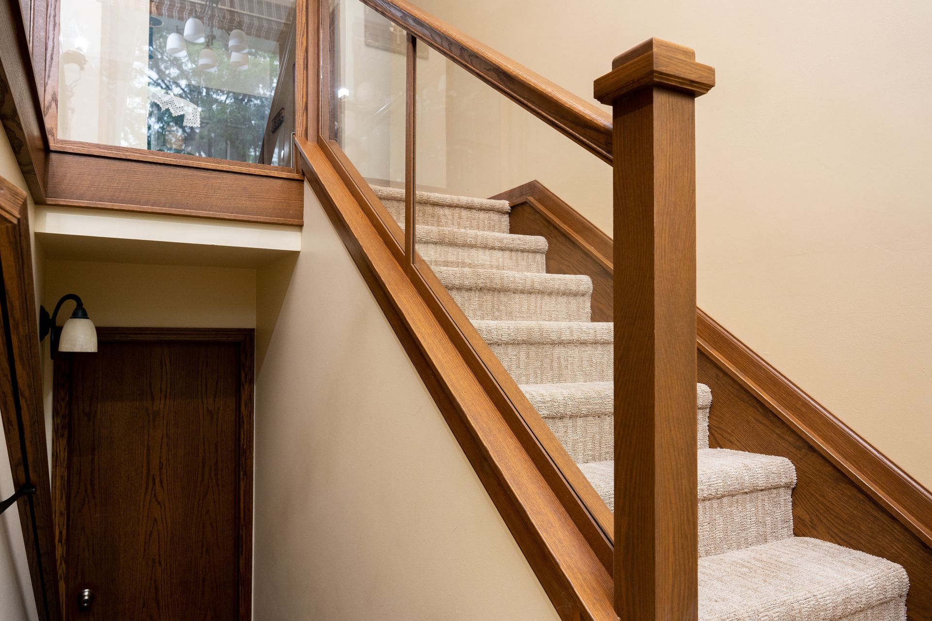 Carpeted staircase with wooden handrails in a beige interior hallway
