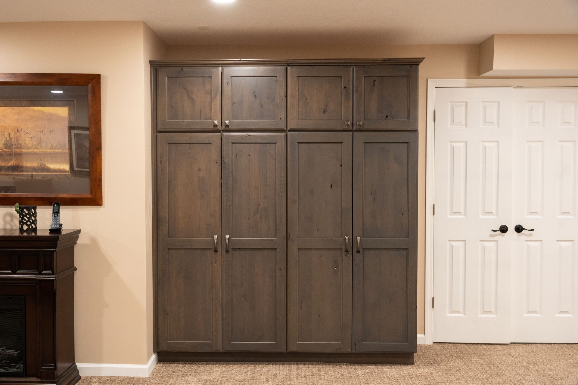 Built-in gray wood cabinet wall beside white double doors in a carpeted room