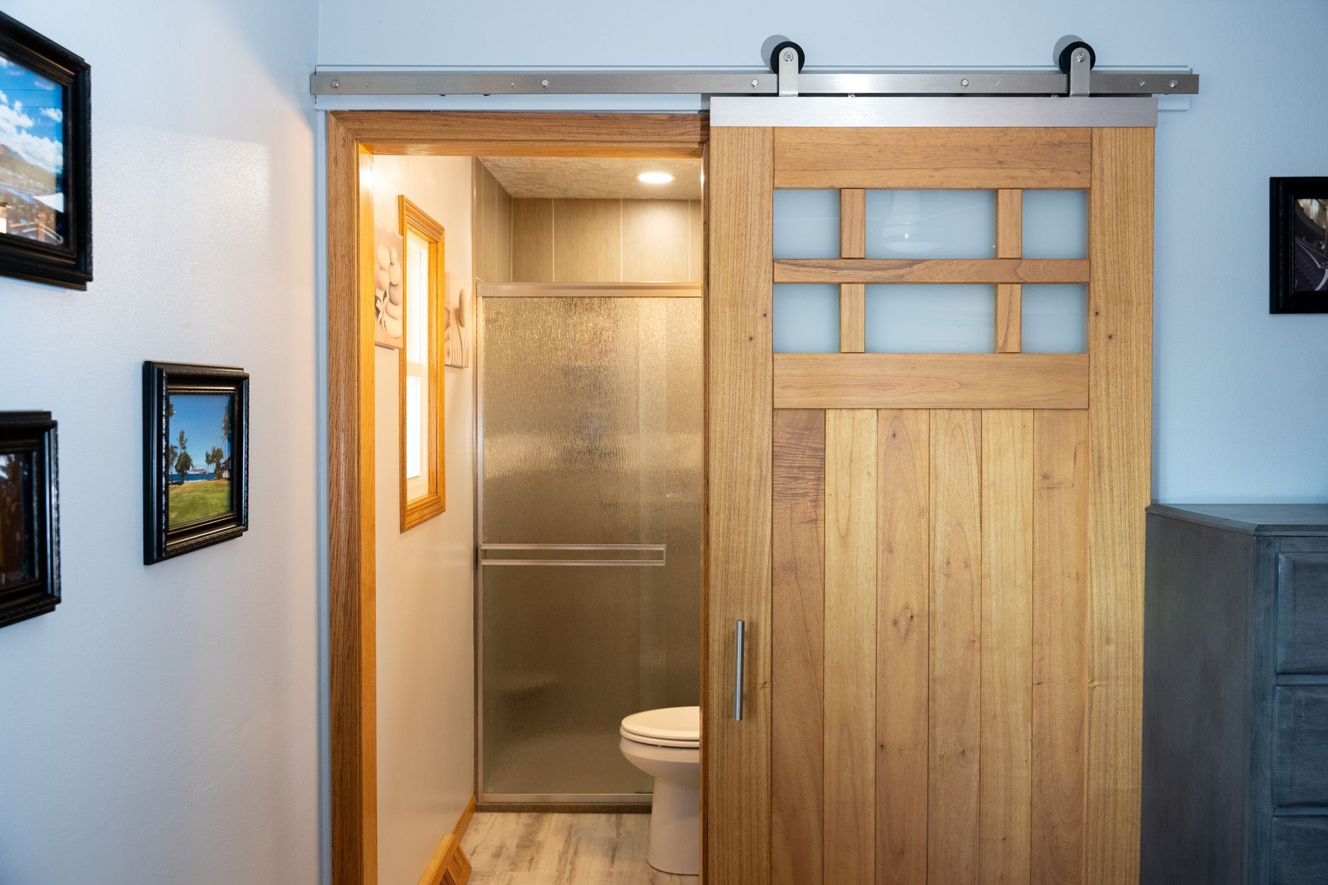 Barn door-style bathroom entrance with a shower and toilet visible inside