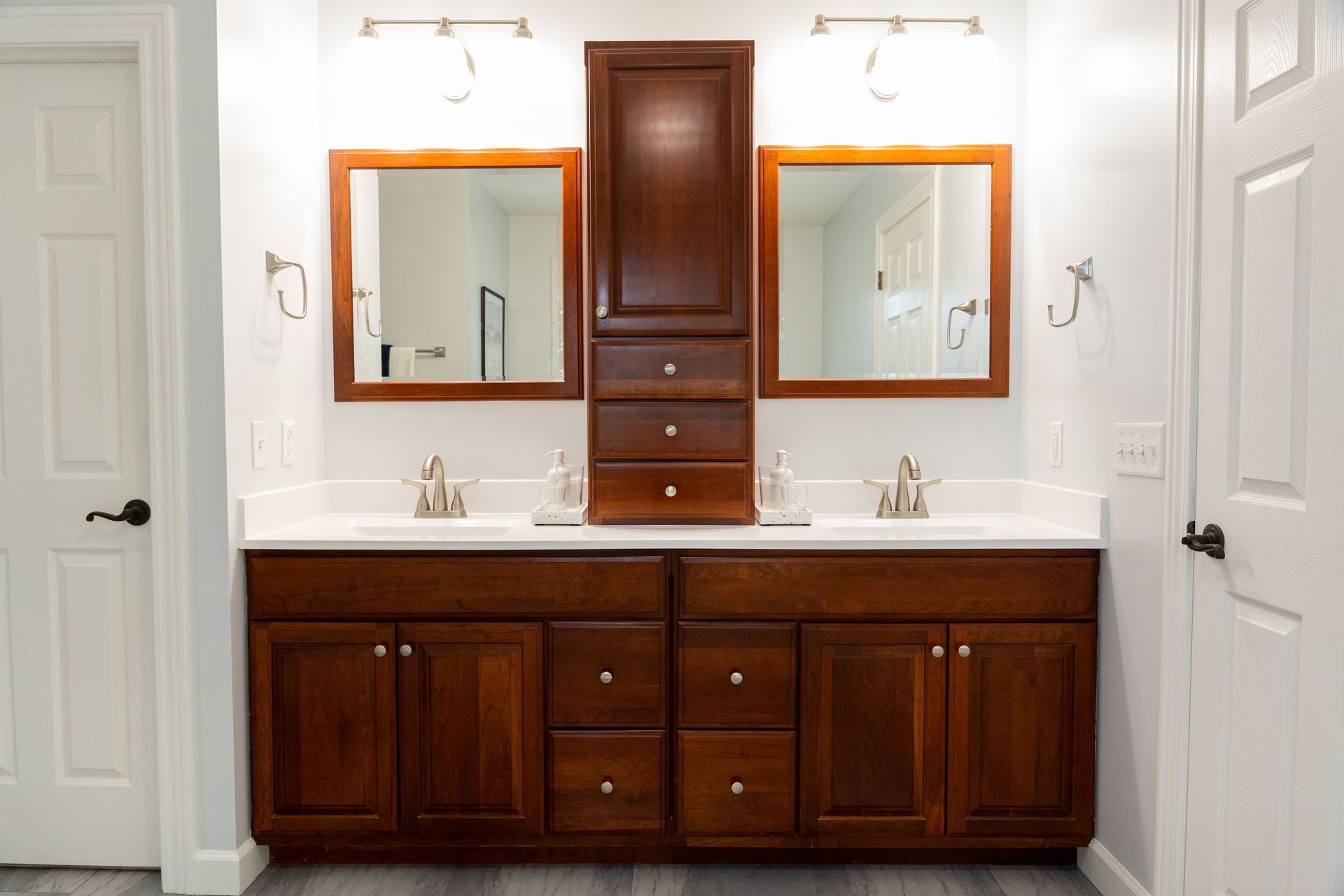 Bathroom vanity with double mirrors, white counters, and dark wood cabinets