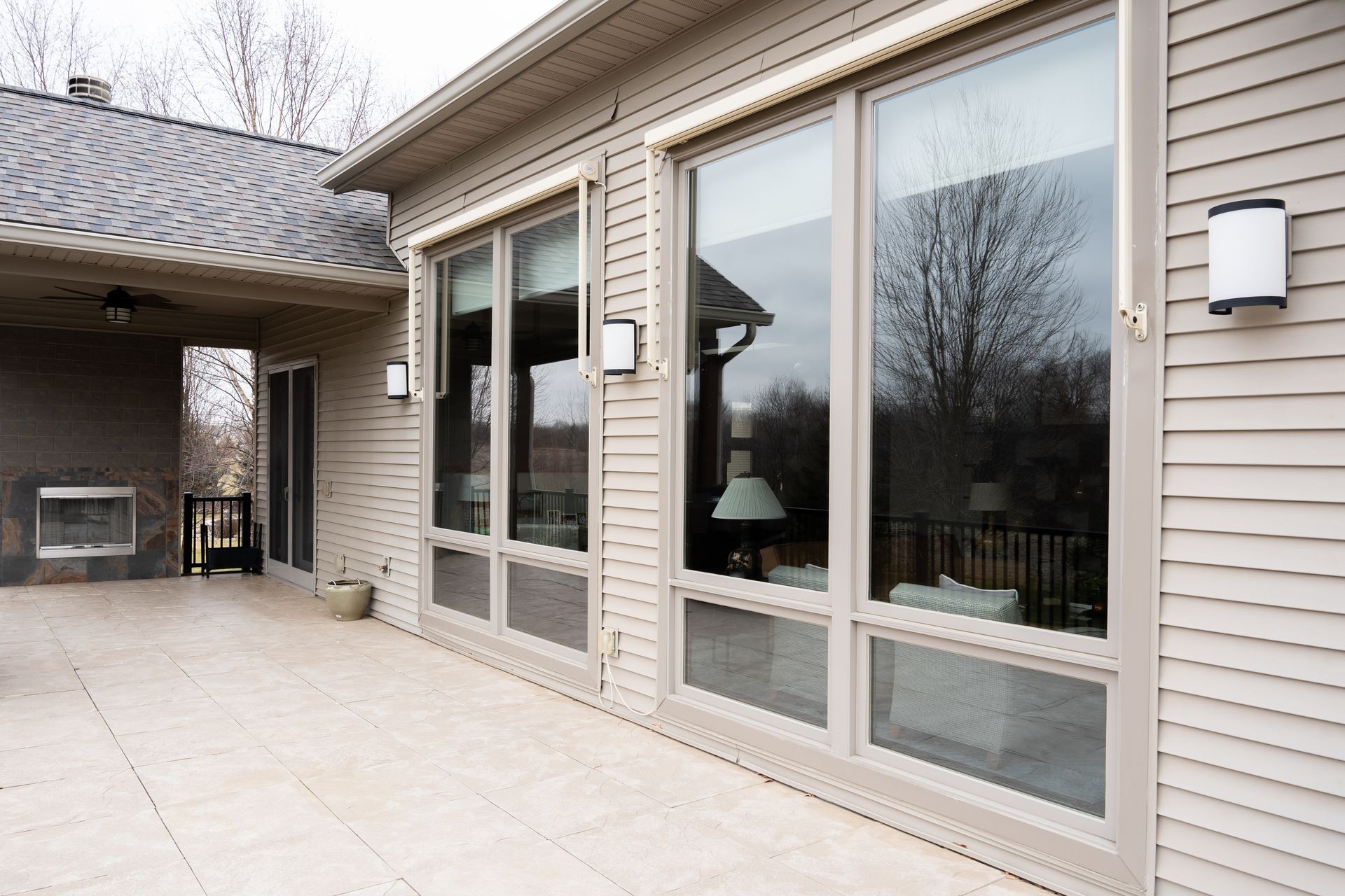 Patio with large windows and sliding glass doors on a beige house