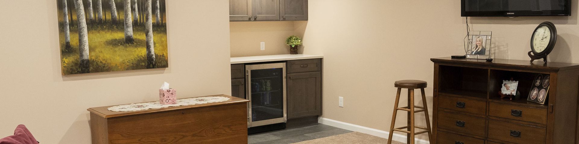 Small apartment kitchen and living area with tan walls, dark cabinets, a coffee table, and TV console.