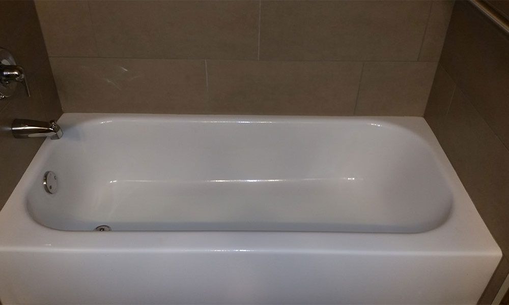 White bathtub in a tiled bathroom, shown from above with faucet fixtures on the left.