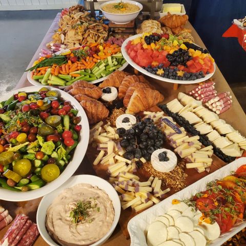 Home Twisted Spoon A table topped with plates of food including vegetables , cheese , fruit , and croissants.