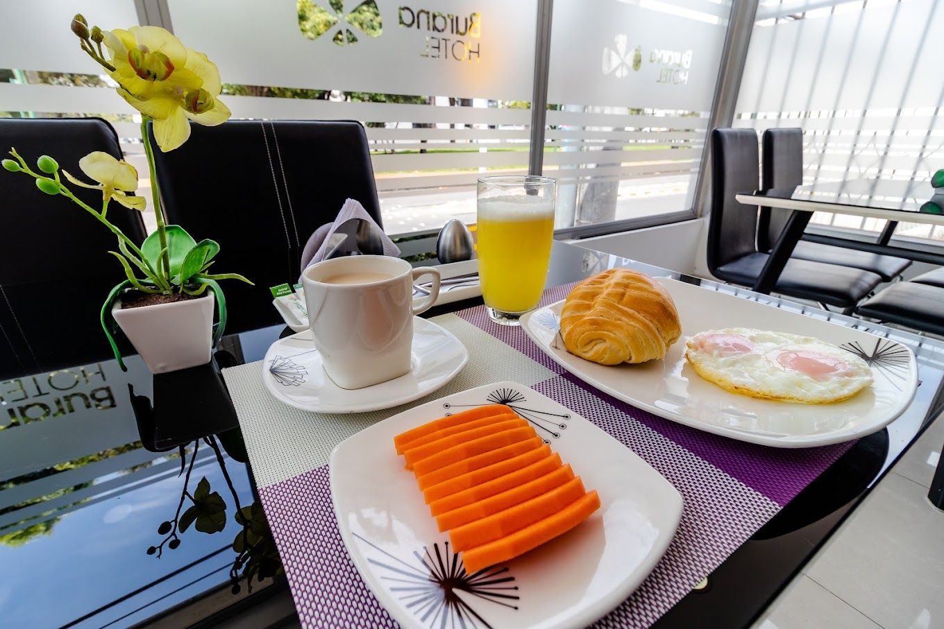 A picture of a fresh breakfast with fruit, juice, eggs, bread and a hot drink