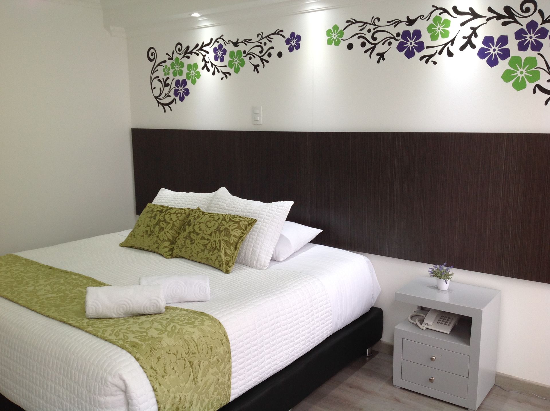 A hotel room with a bed and a nightstand
