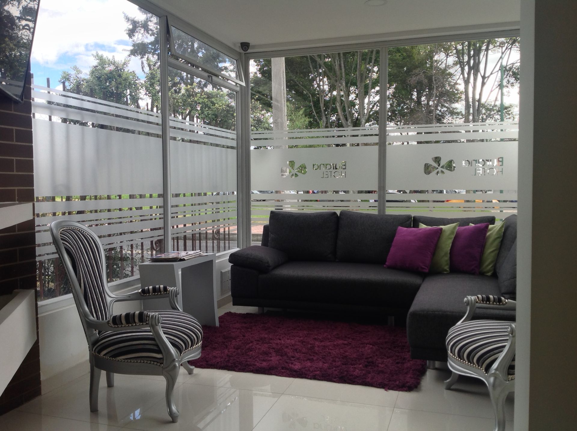 A living room with a black couch and purple pillows