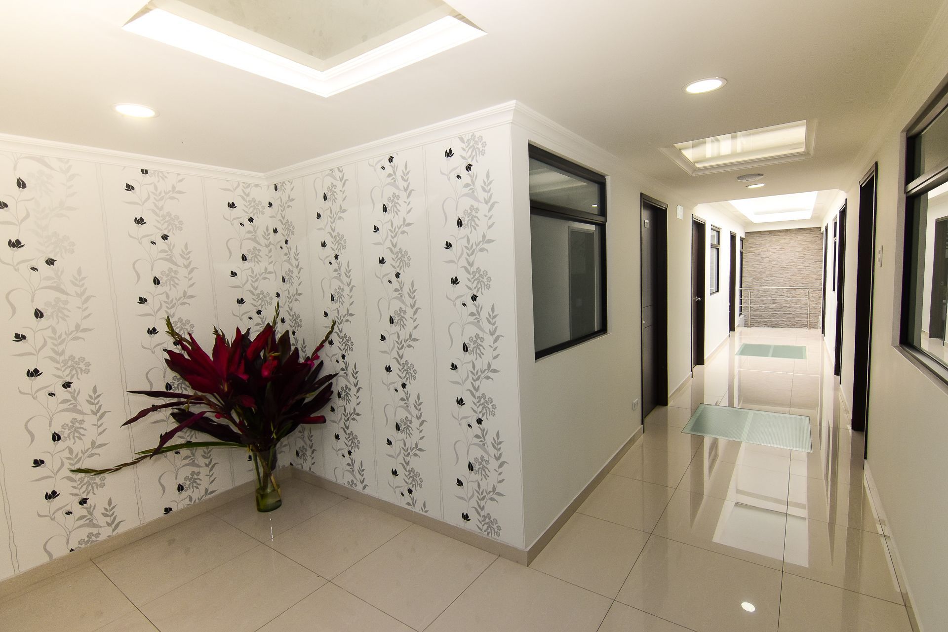 A long hallway with a vase of flowers on the floor.