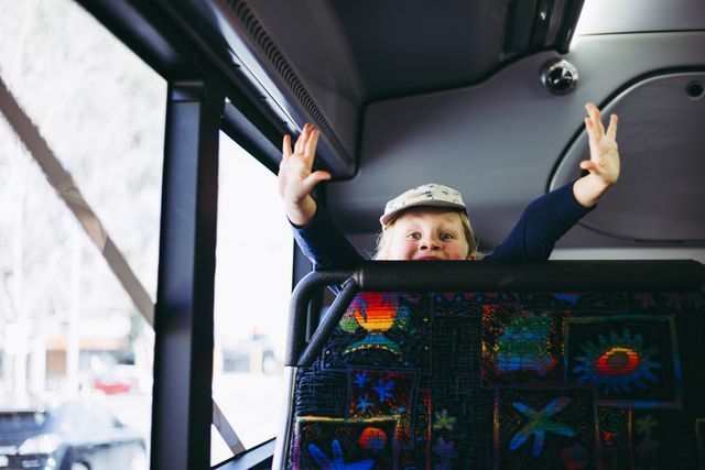Child With Raised Arms Sits on a Bus Seat — J & B Bus and Coach Pty Ltd In Kingscliff, NSW