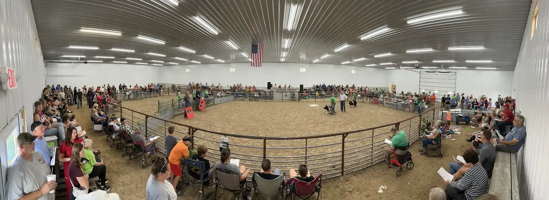 Wide crowd gathered around a circular animal enclosure in a bright indoor arena