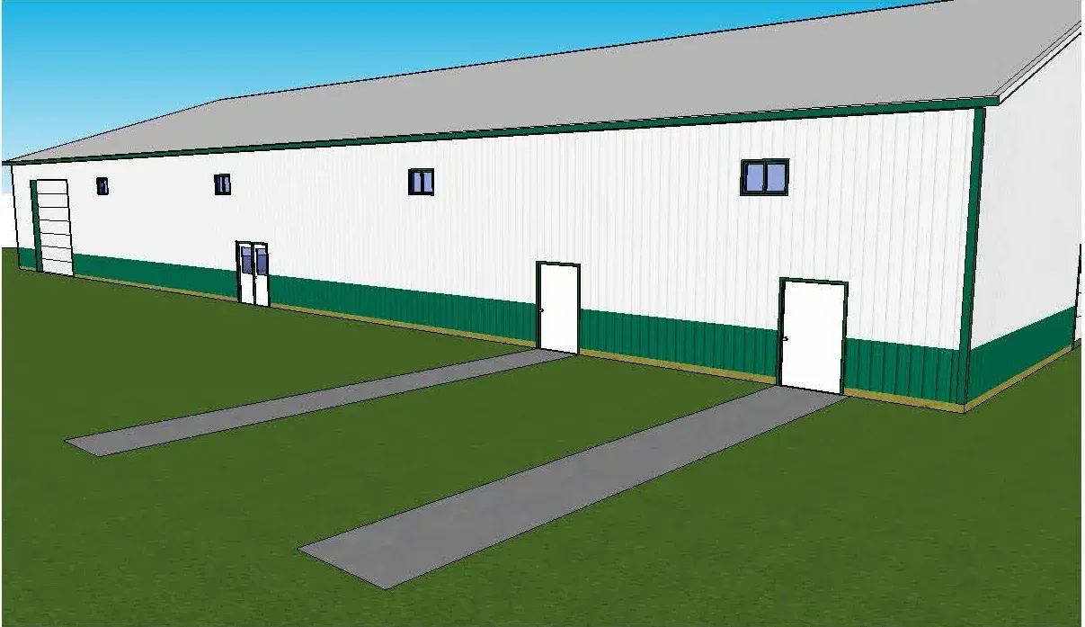 White warehouse building with green trim and two loading ramps on a grassy lot