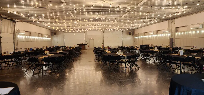 Elegant banquet hall with chandeliers, long tables, and black chairs set for an event