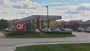 QT gas station with red and white signage; cars parked at pumps and nearby building; cloudy sky.