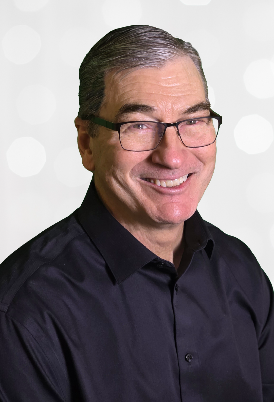 Smiling man wearing glasses and a black shirt, set against a blurred background with white circles.