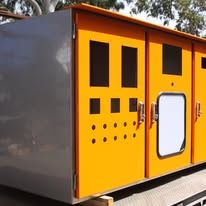 Yellow and gray utility kiosk with black panels and a white access door outdoors