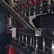 Close-up of industrial machinery with black metal parts, red cables, and a diagonal conveyor or chute