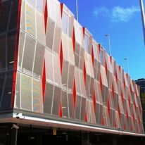 Modern building facade with white panels, red accents, and blue sky above