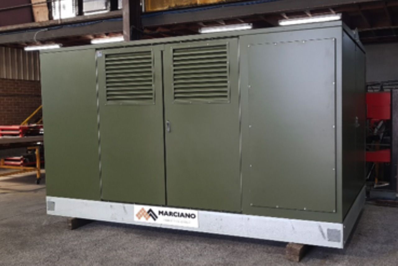 Large olive-green industrial machine cabinet on a white base in a warehouse setting