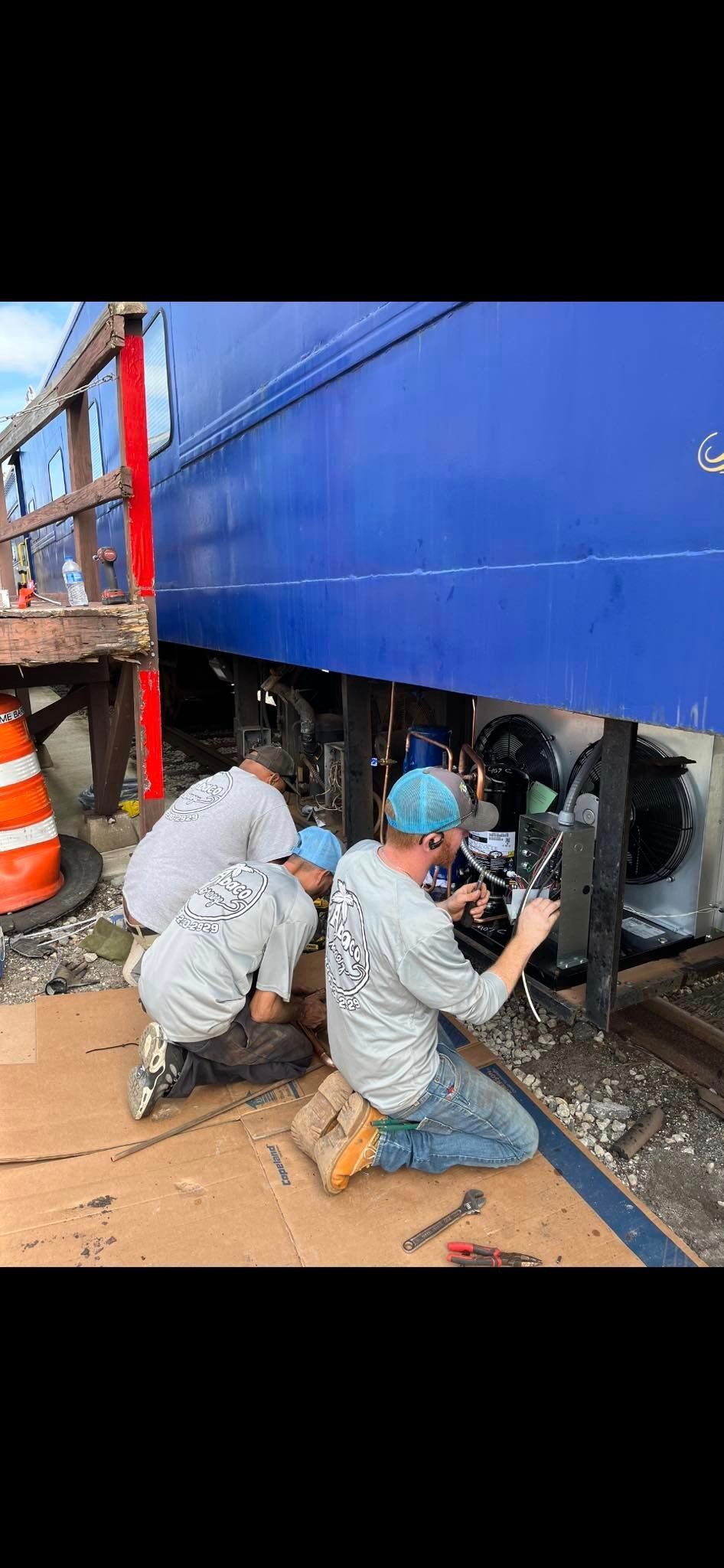 A group of men are working on a blue train.