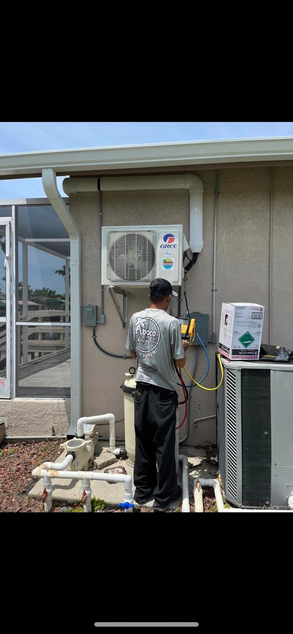 A man is working on an air conditioner outside of a house.