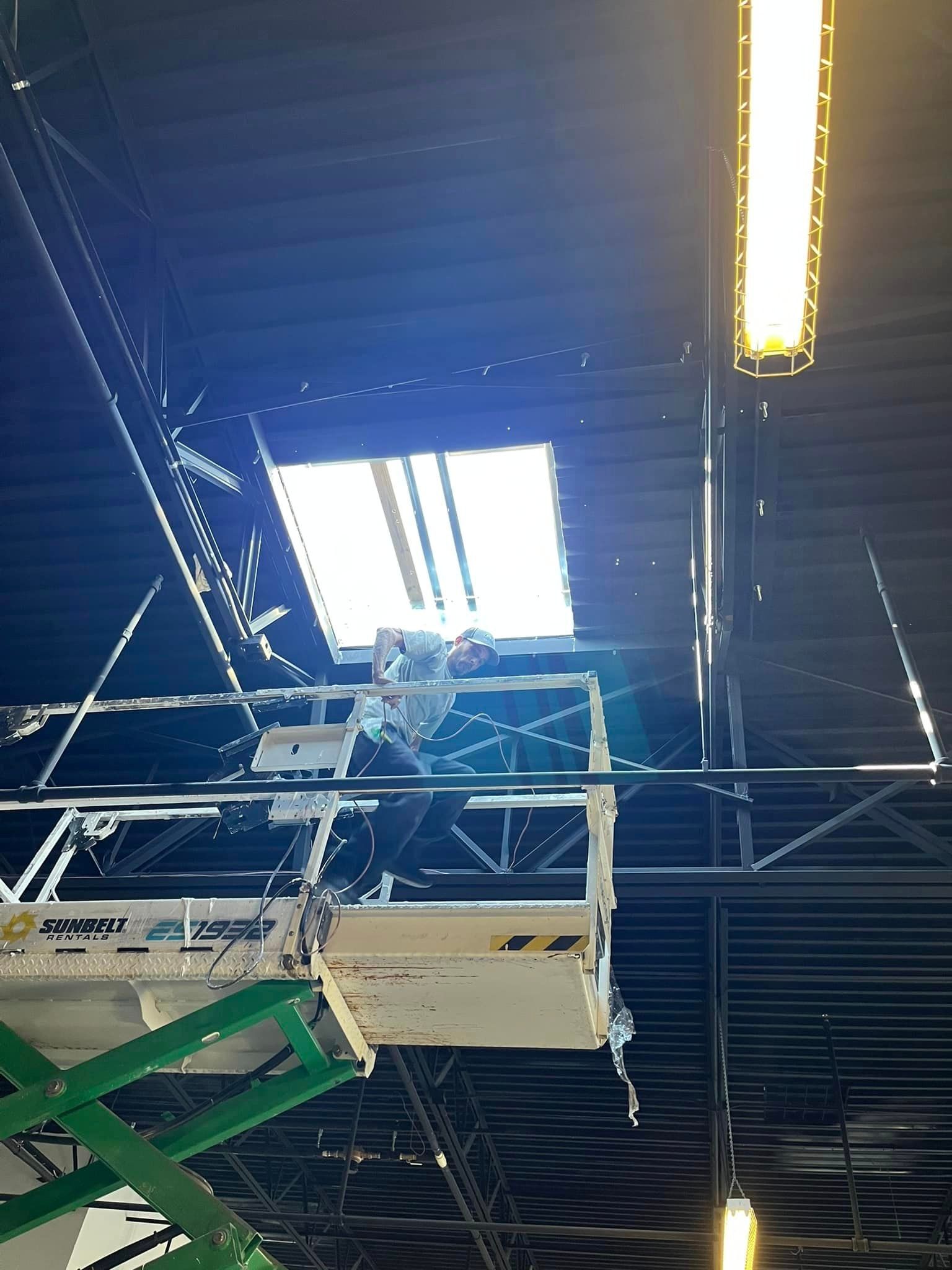 A man is working on the ceiling of a building on a lift.