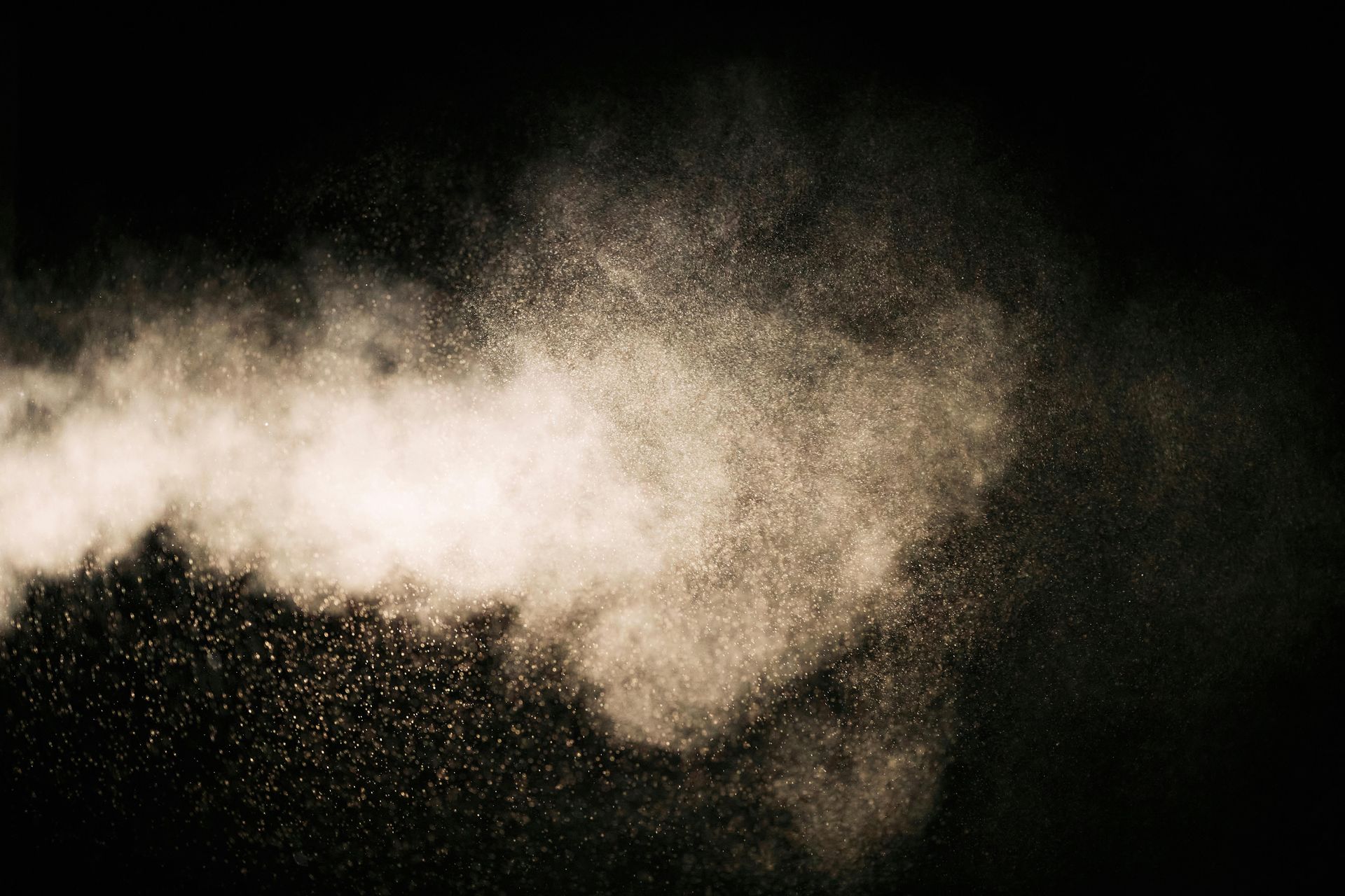 A close up of a smoke coming out of a pipe on a black background.