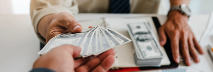 A man is handing a stack of money to another man.