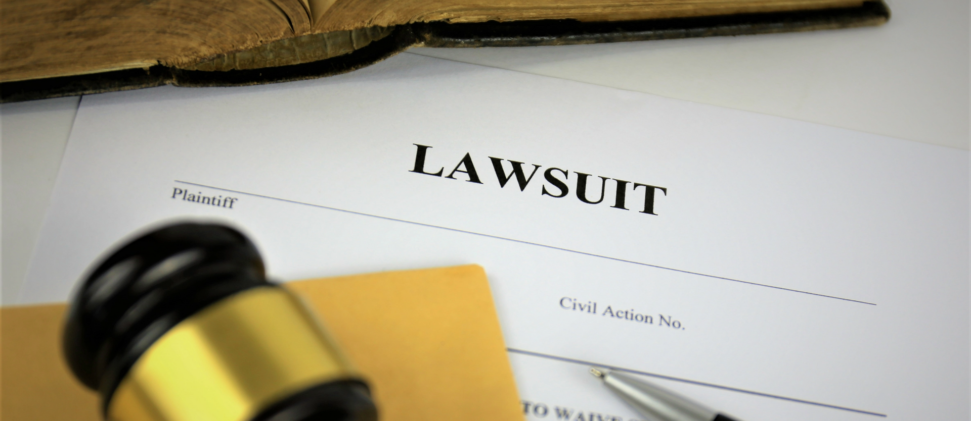 A lawsuit form with a gavel and pen on top of it.