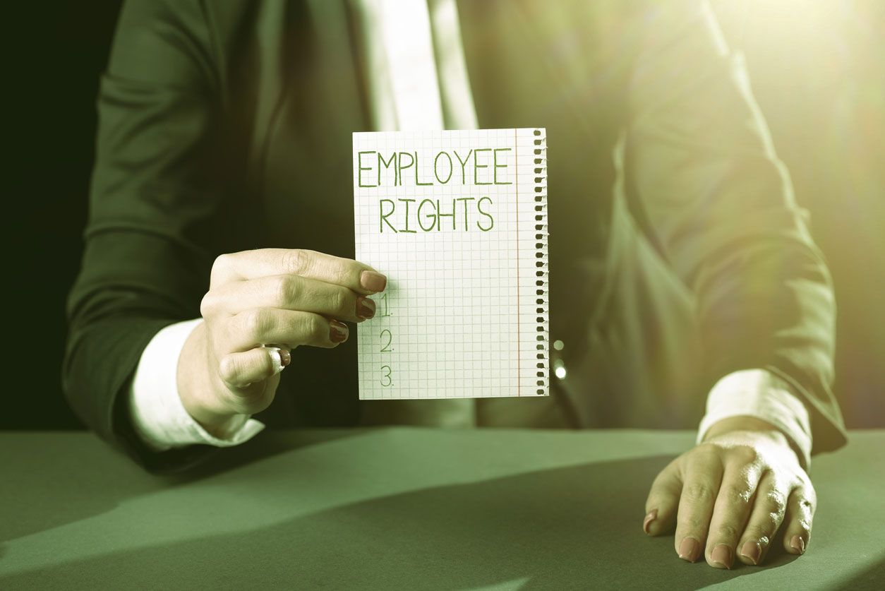 Angry looking man points at another man with his head in his hands at an office desk.