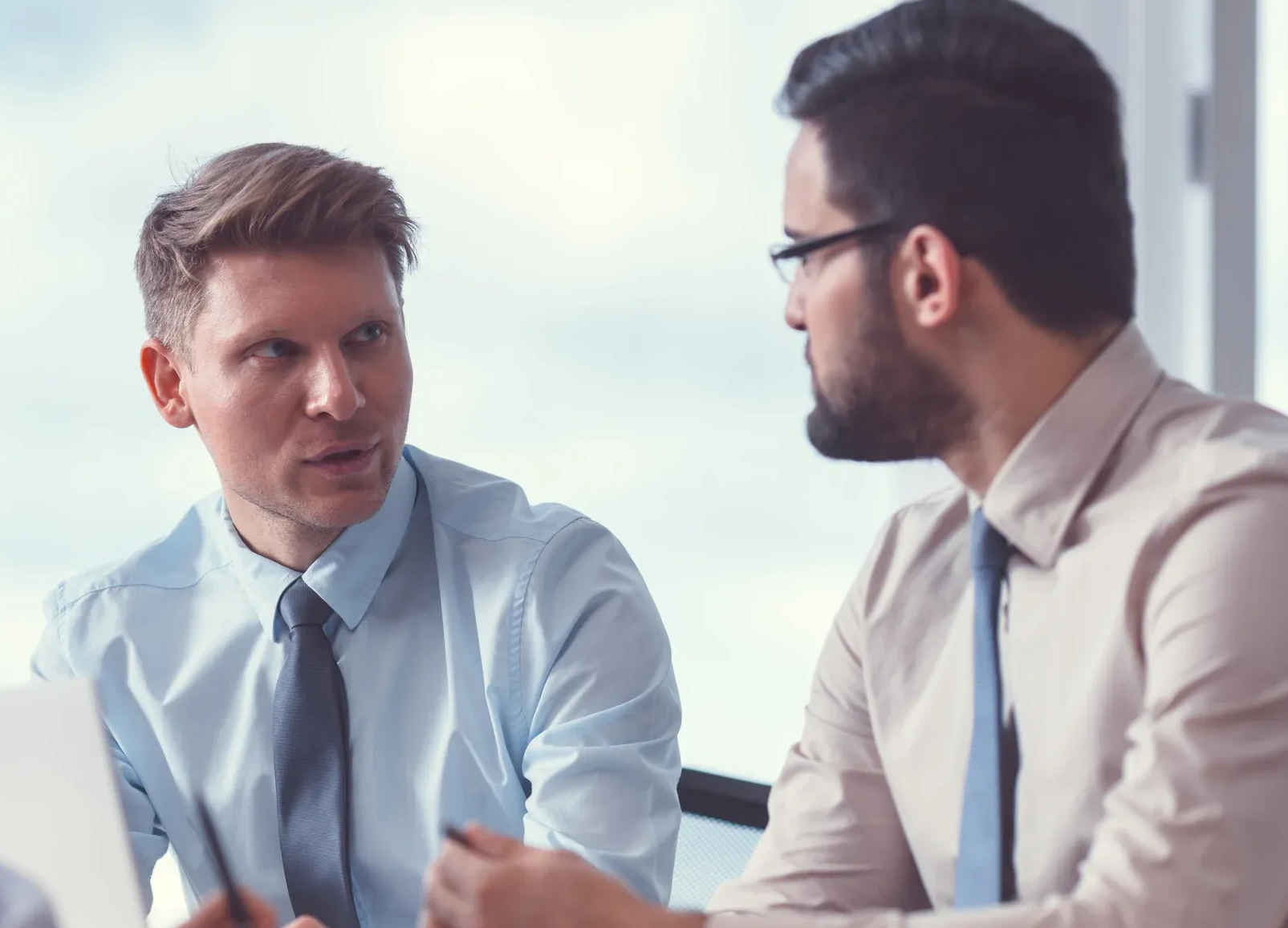 Two men in business attire having a discussion, one holding a paper.