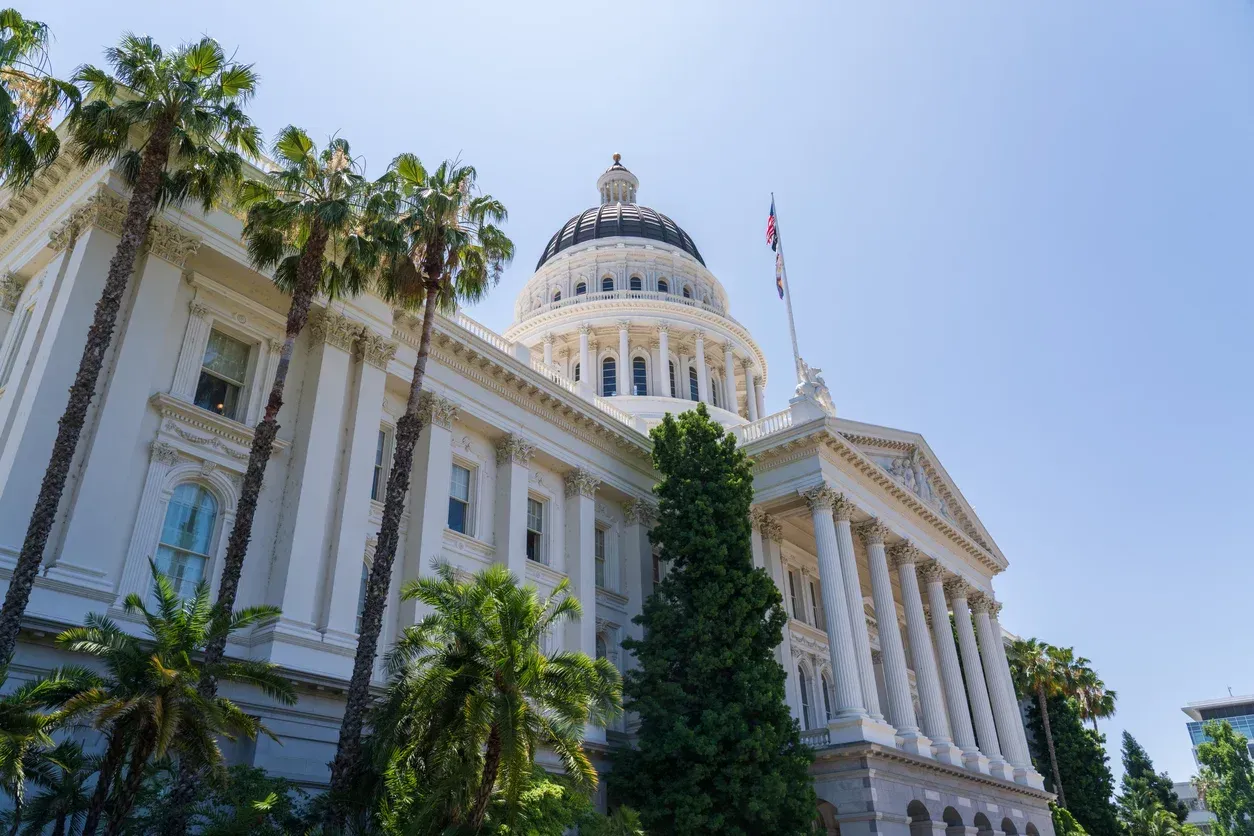 California State Capitol building with palm trees against a blue sky.