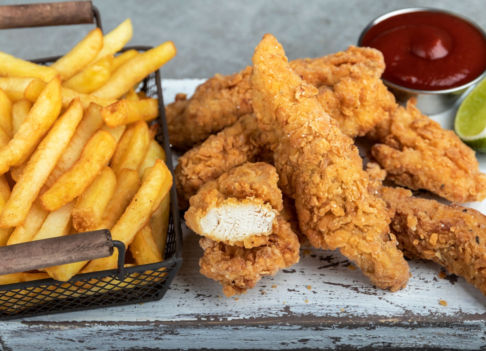 Fried chicken tenders and fries with ketchup and lime wedges on a tray