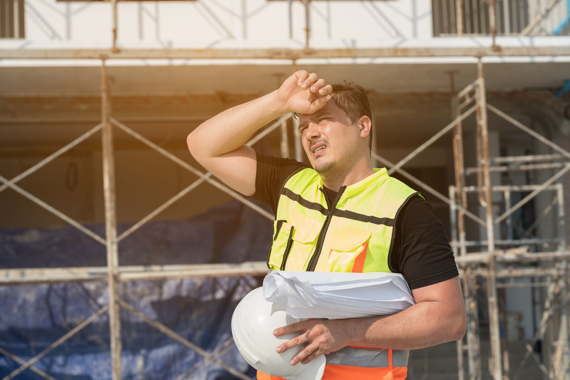 An outdoor worker wiping sweat from his forehead.