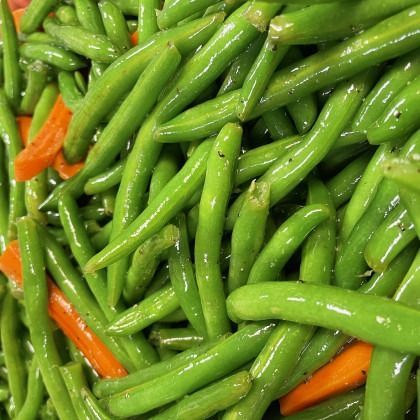 Close-up of glossy green beans mixed with a few orange carrot strips