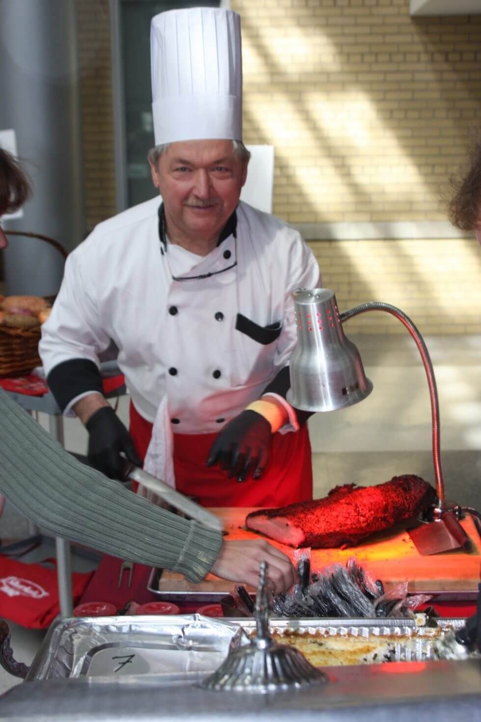 Chef carving roast at a buffet under a heat lamp