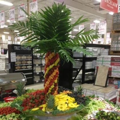 Colorful palm tree made of fruit and flowers displayed in a grocery store produce section