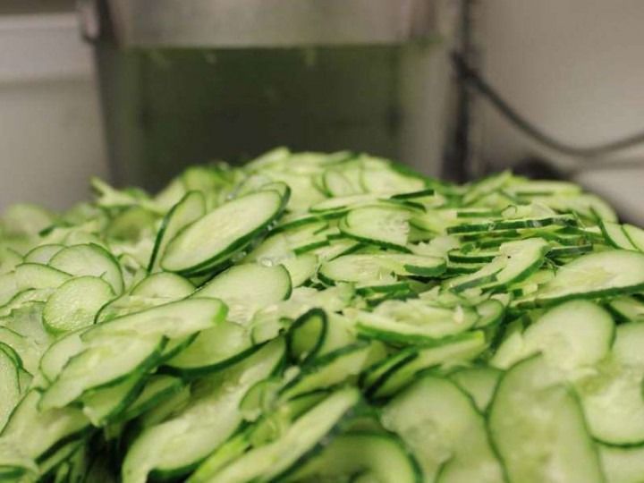 Thinly sliced cucumbers piled on a tray, ready for food preparation