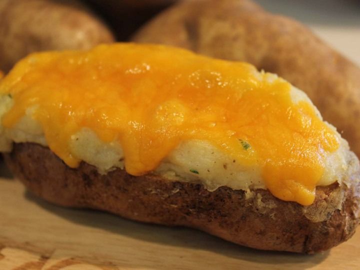 Baked potato topped with melted cheddar cheese on a plate