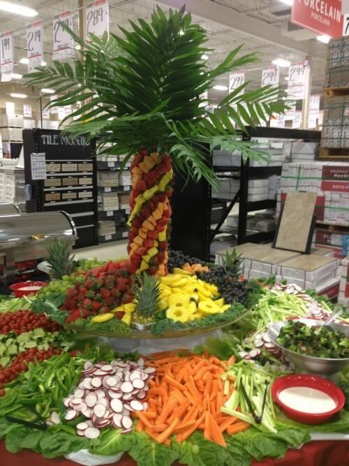 Decorative vegetable display shaped like a palm tree with colorful produce in a grocery store aisle