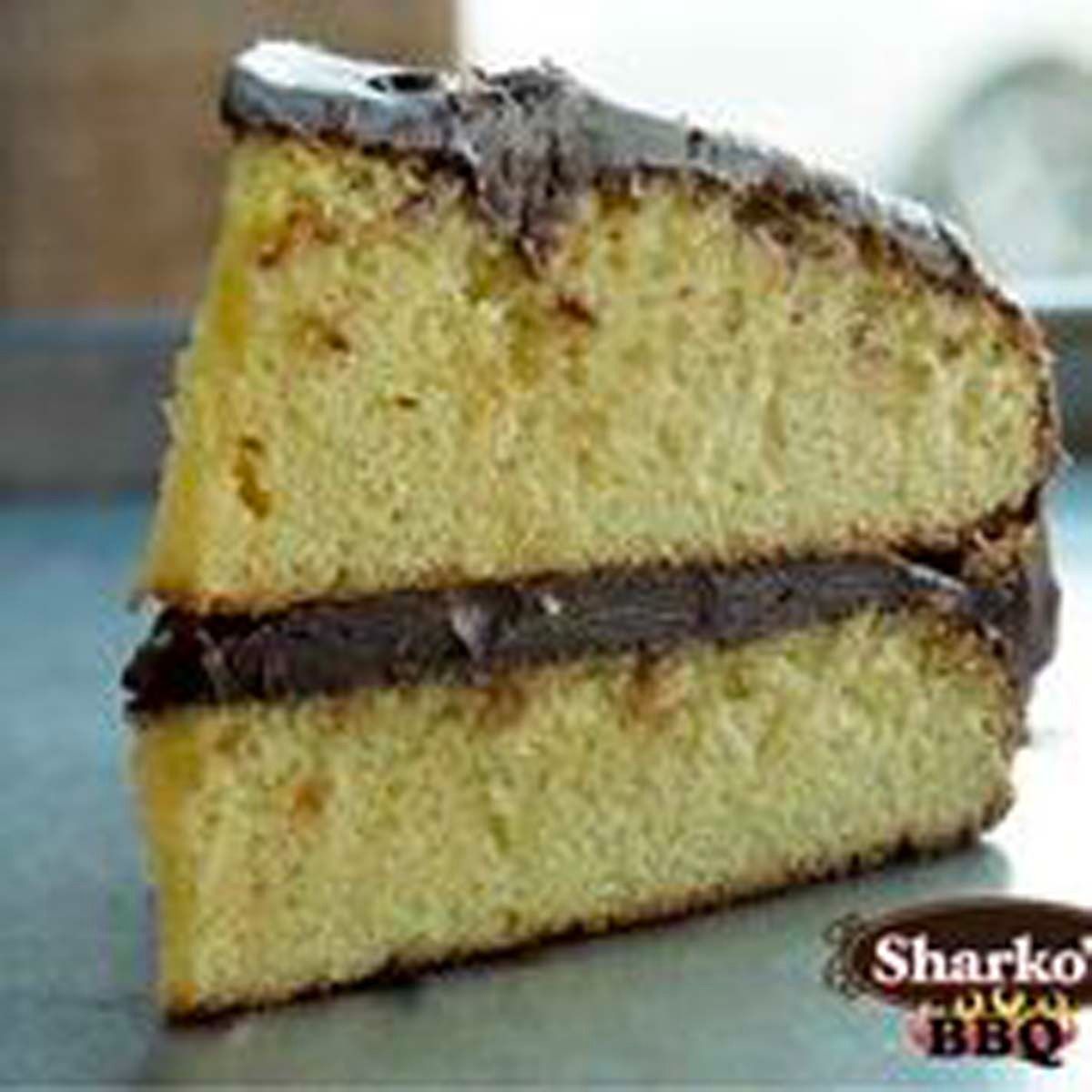 Two slices of yellow sponge cake with chocolate filling and frosting on top, stacked on a plate