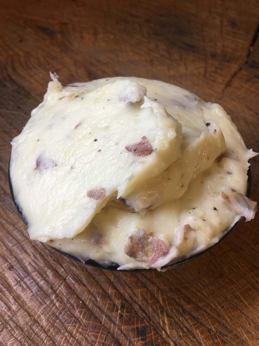 Scoop of vanilla ice cream with nut and chocolate bits on a wooden surface
