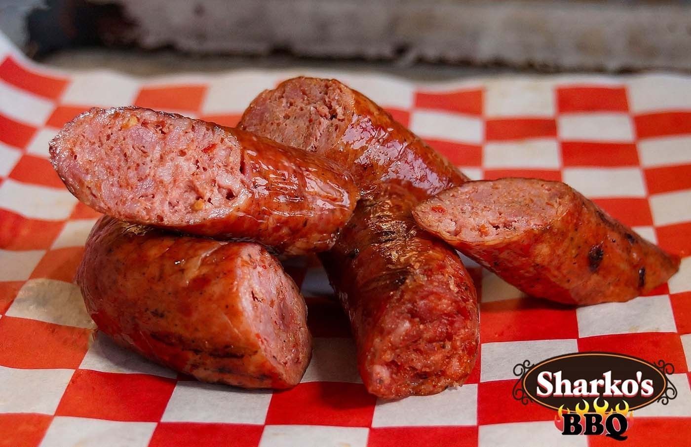 Sliced BBQ sausage on red-and-white checkered paper with Sharko's BBQ logo