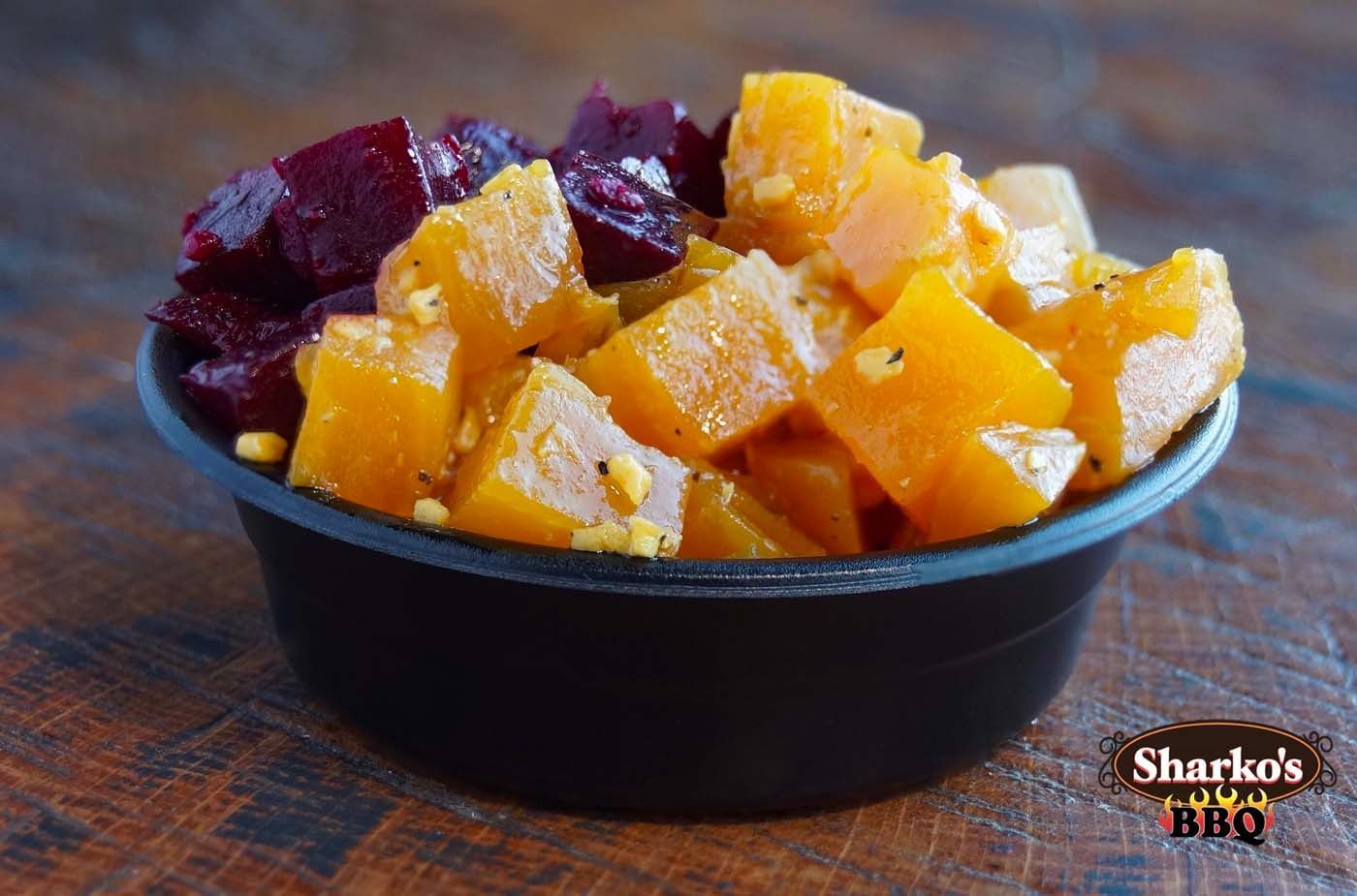 Black bowl of diced orange and red fruit on a wooden table