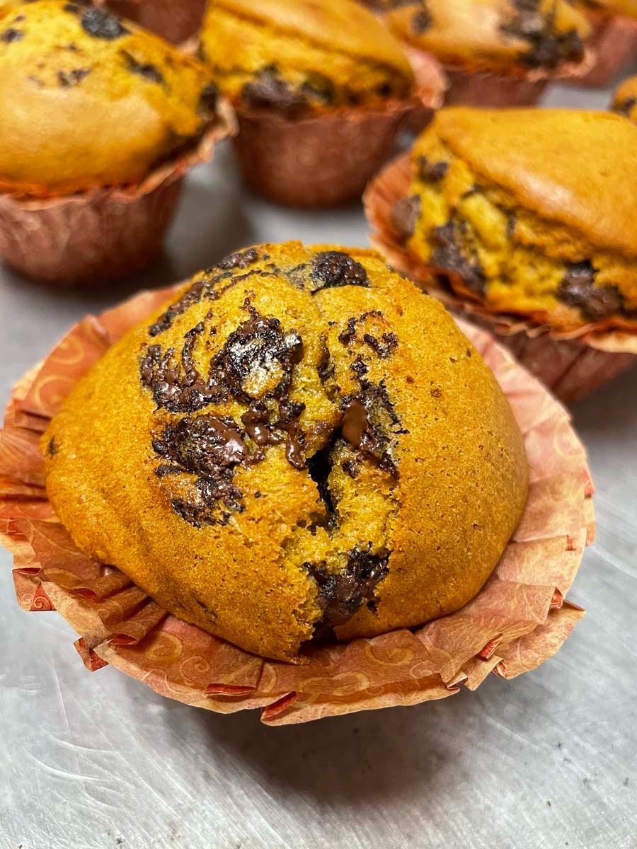 Close-up of golden-brown muffins with chocolate swirls in paper cups on a tray