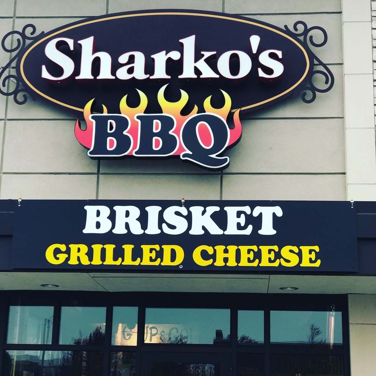 Sharko’s BBQ sign advertising brisket grilled cheese on a storefront.