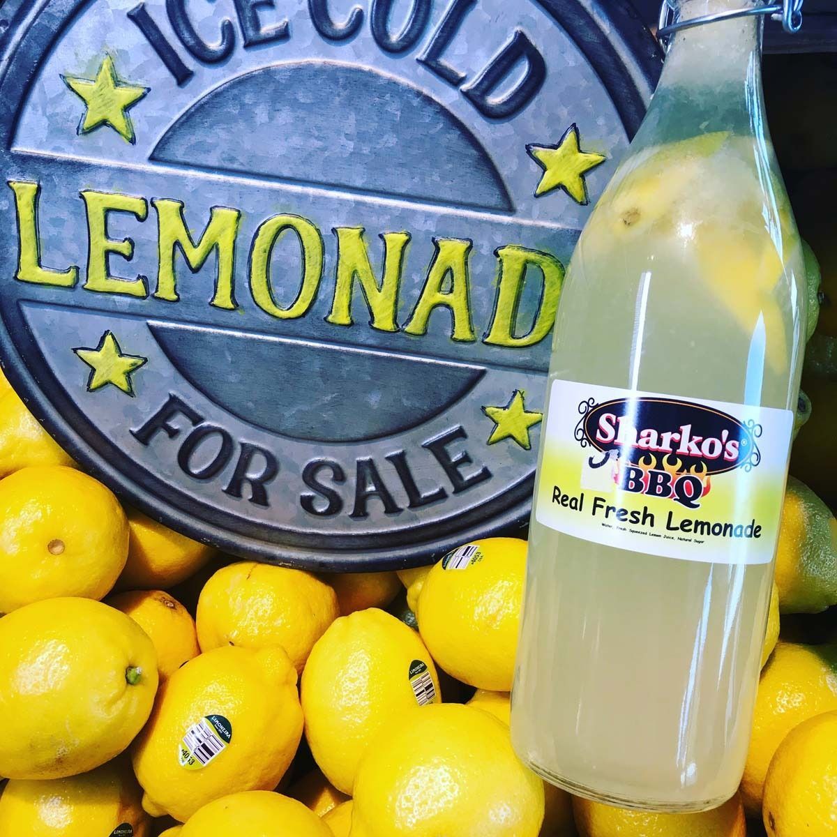 Ice-cold lemonade sign with lemons and a bottle of fresh lemon drink