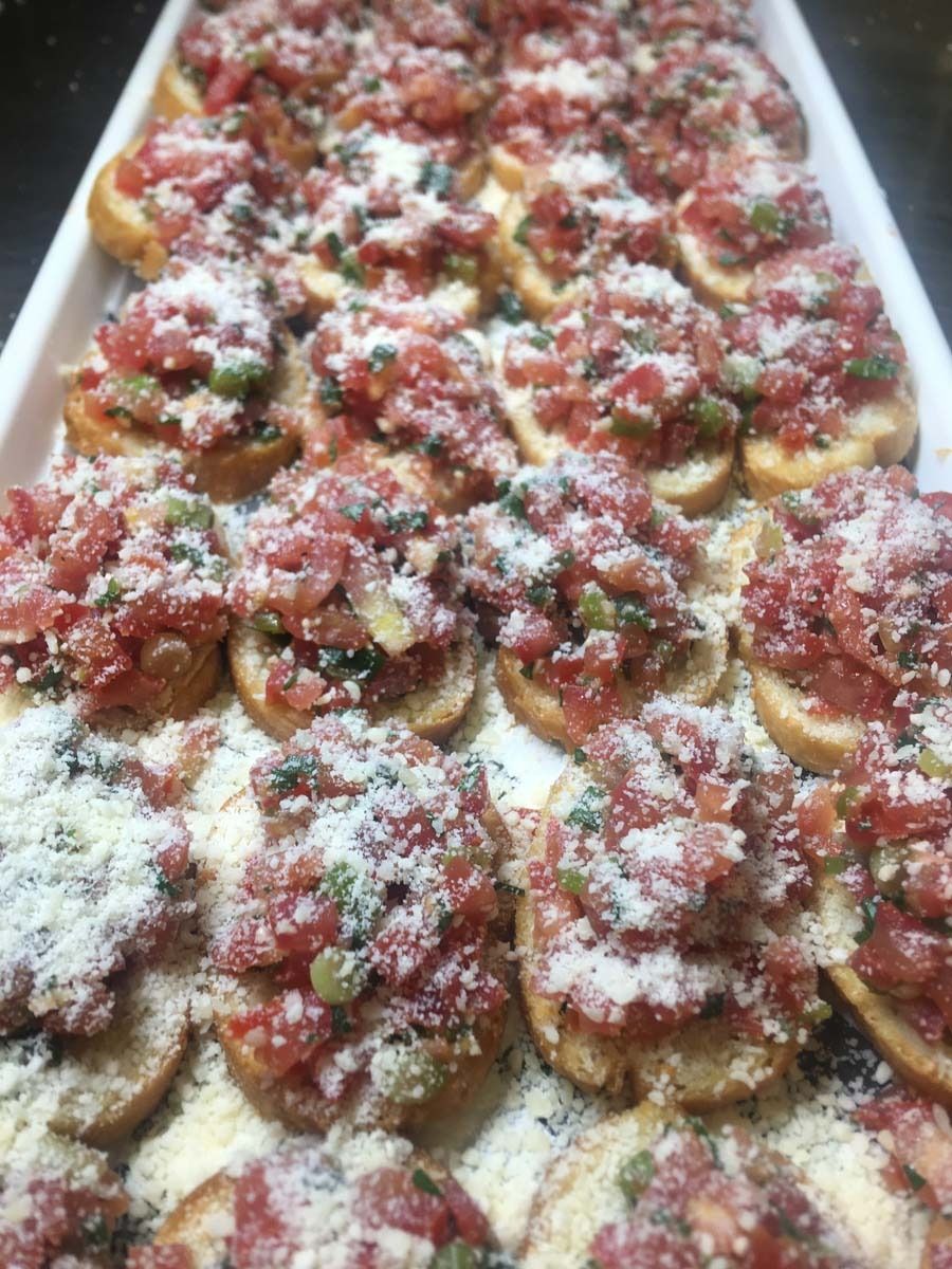 Tray of mini pastries topped with red sauce, herbs, and grated cheese