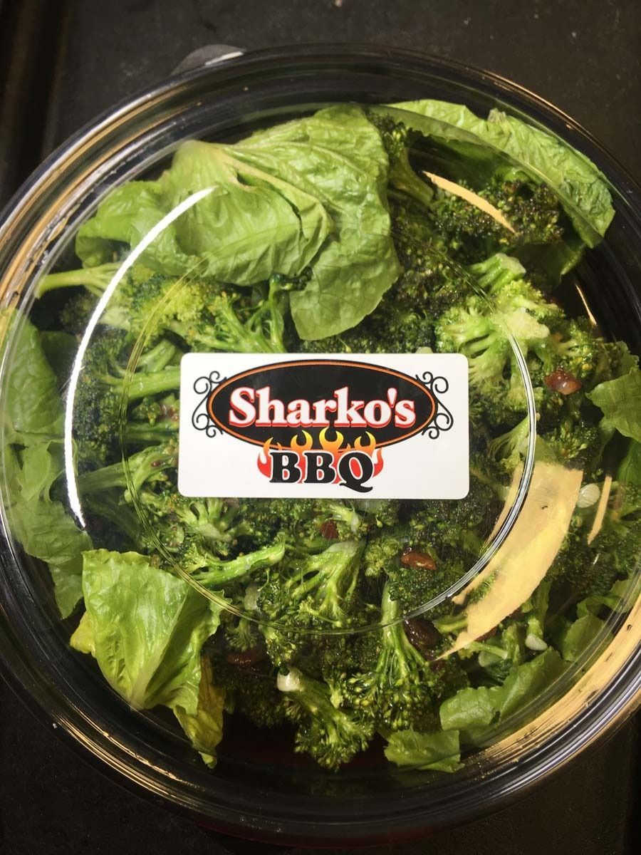 Sharko’s BBQ salad in a clear plastic bowl with mixed greens and dressing on top